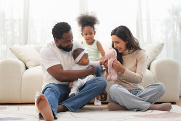 Obraz premium Loving interracial family sitting on floor,playing with kids in living room,bonding african kid with father and mother at home