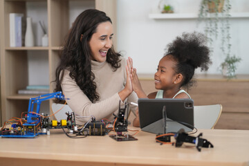 african kid learning robot circuits on tablet computer,caucasian tutor helps a student in STEM lesson in class,teacher and child giving high five together