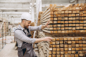 Carpenter inspecting wooden planks in lumber warehouse