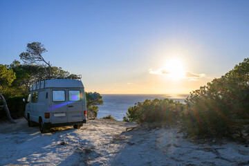 Old motorhome on the beach with sun and sea in the background, Mallorca, Spain