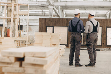 Construction workers discussing prefabricated building project in factory