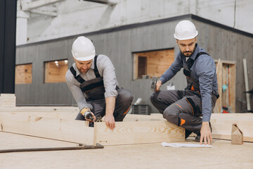 Construction workers assembling modular building components in factory