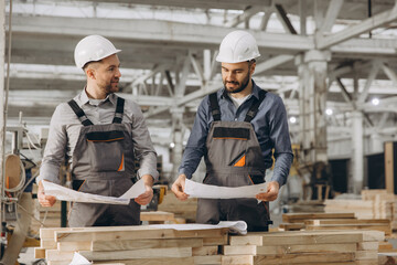 Construction workers examining blueprint in modular building factory