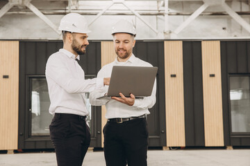 Engineers using laptop discussing modular building project