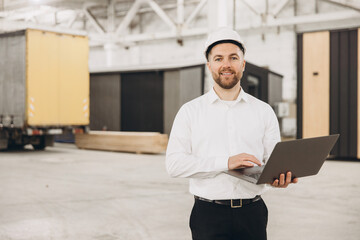 Engineer using laptop in modular building factory: prefabrication and construction industry