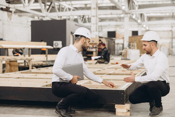 Engineers inspecting wooden frame for modular building in factory