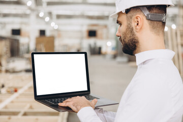 Architect using laptop with white screen in modular building factory
