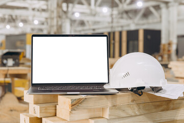 Laptop with blank screen, helmet and blueprint showing modular building industry