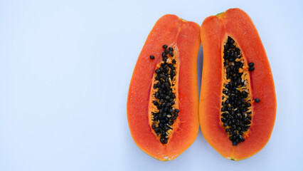 A ripe papaya cut in half  chop block. on a white background.