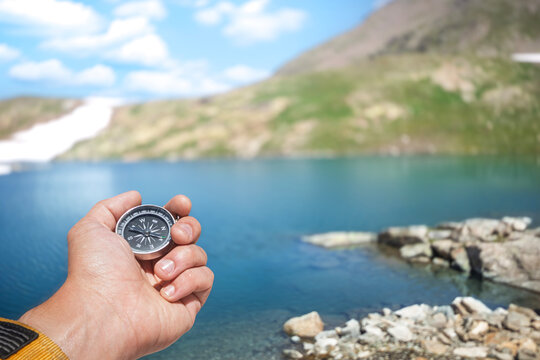 Traveler Holding a Compass Against a Mountain Lake in the Caucasus