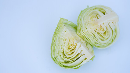 A cabbage cut in half, showcasing its fresh green leaves and internal layers, isolated on a plain white background