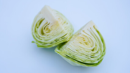 A cabbage cut in half, showcasing its fresh green leaves and internal layers, isolated on a plain white background