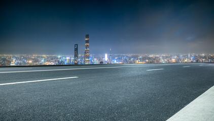 Empty asphalt road and modern city skyline at night