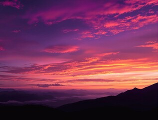Obraz premium A stunning sunset over a mountainous landscape, showcasing vibrant purple and orange hues in the sky.