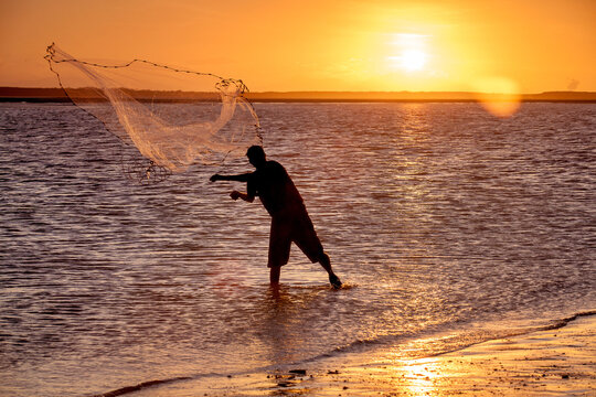 Fisherman throwing a cast net at sunset.