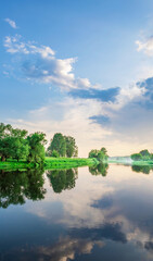 Calm lake with trees in the background and a cloudy sky