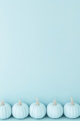 Light blue pumpkins line a smooth pastel background creating a serene autumn vibe in a cozy indoor setting