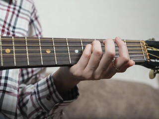 Close-up of female hands skillfully playing an acoustic guitar, practicing intricate chords and...