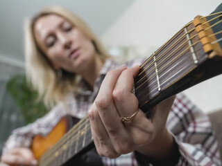 Close-up of a woman's hands skillfully playing chords on an acoustic guitar, crafting beautiful...