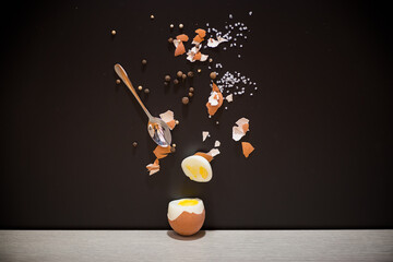 Boiled egg with spices and shell on black background