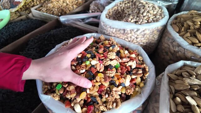 Assorted dried fruits in a bag: walnuts, dried apricots, peanuts, raisins, cashews, almonds, at an open eastern market