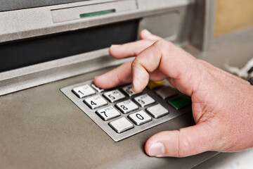 Man's hand at an ATM, entering PIN