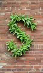 A green fern arrangement forms the shape of the number three on a textured brick wall.