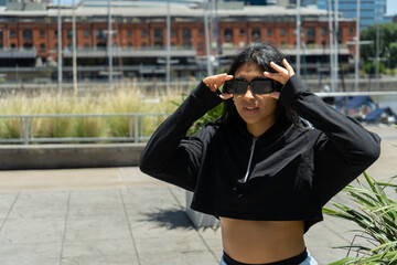 Fototapeta premium Latin woman adjusting sunglasses in urban setting, puerto madero, buenos aires
