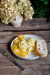 Scrambled eggs with cheese, yellow tomato and bread