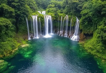 Obraz premium Majestic Waterfall Surrounded by Lush Greenery in Tropical Paradise with Crystal Clear Water Pooling Below