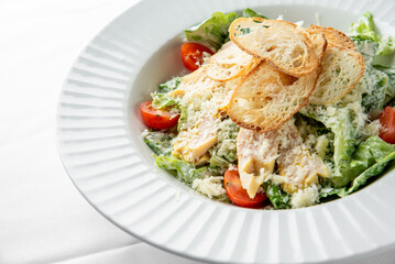 Fresh Caesar salad with grilled chicken, cherry tomatoes, and crispy bread slices, presented in a stylish white bowl. Perfect for healthy dining and gourmet cuisine.