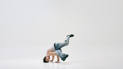 Talented dancer demonstrating gravity-defying spin, shows himself through movement against white background. Concept of performance, art, music, dancer, athleticism, control, movement.