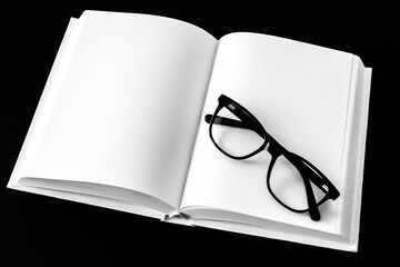 Black reading glasses are lying on a white notepad. Space for text