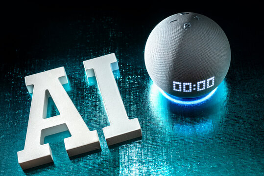 Letras tridimensionales con el texto AI junto a un dispositivo Amazon Echo Dot con luz azul activada, reflejando la integraci&oacute;n de la inteligencia artificial en Alexa.