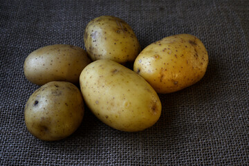 five raw potatoes resting on a rustic burlap fabric