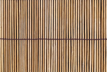 Close-up of the back of a bamboo mat with brown threads used as a background.