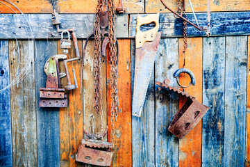 Old vintage rusty household tools on colorful wood board background.