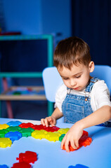 Child playing with colorful blocks. A young boy concentrates on assembling colorful plastic...