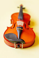 brown wooden graceful sexy lacquered violin, musical instrument lies on a gentle yellow background...