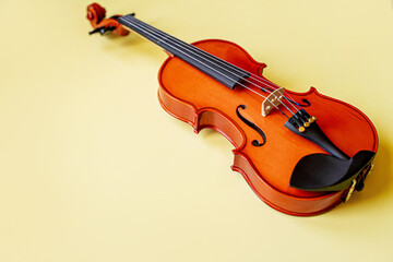 brown wooden graceful sexy lacquered violin, musical instrument lies on a gentle yellow background...