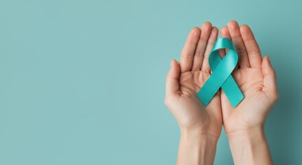 Sexual Assault Awareness Month concept. Hands of woman holding teal ribbon on blue background.  Symbolic for cervical cancer, ovarian cancer, gynecological cancer and PCOS. 