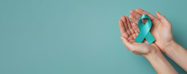 Sexual Assault Awareness Month concept. Hands of woman holding teal ribbon on blue background.  Symbolic for cervical cancer, ovarian cancer, gynecological cancer and PCOS. 