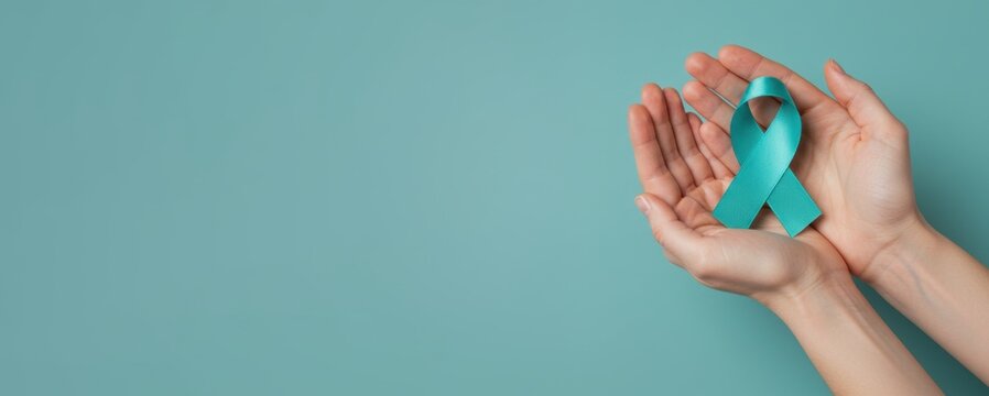 Sexual Assault Awareness Month concept. Hands of woman holding teal ribbon on blue background.  Symbolic for cervical cancer, ovarian cancer, gynecological cancer and PCOS.  - Powered by Adobe