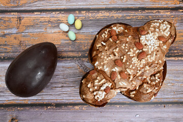 Colomba pasquale or Easter Dove is a traditional Italian dessert prepared with sourdough, almonds and candied fruit top view whit chocolate egg