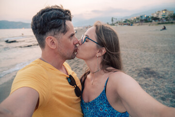 Happy couple taking a photo on a beach at the sea in Alanya city, Turkey. Travelling or vacation concept