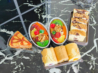 Variety of cakes and fruit desserts on a dark marble surface.