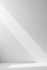 A Minimalist White Wall with a Diagonal Light Beam Casting Shadows on a Clean Surface