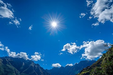 Bright sun shining over majestic mountains and clouds in a clear blue sky