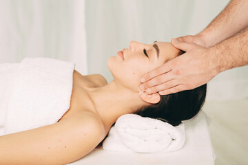 Woman relaxing with eyes closed during head massage at wellness resort. Massage head pain treatment