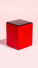 Fototapeta premium Red cube with a black top, sitting on a light pink background. Studio lighting casts a subtle shadow.